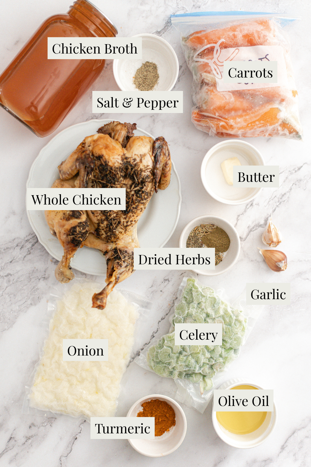 Ingredients for Homestyle Chicken Noodle Soup arranged on a marble surface, featuring a whole roasted chicken, chicken broth, carrots, onion, celery, butter, garlic, olive oil, dried herbs, turmeric, salt, and pepper.