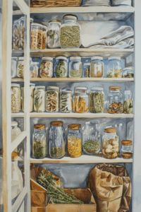 A pantry shelf filled with glass jars containing dried herbs, pasta, and spices. Some jars have cork lids. There are also paper bags, a basket, and folded linens on the shelves. Natural light streams in from the left.